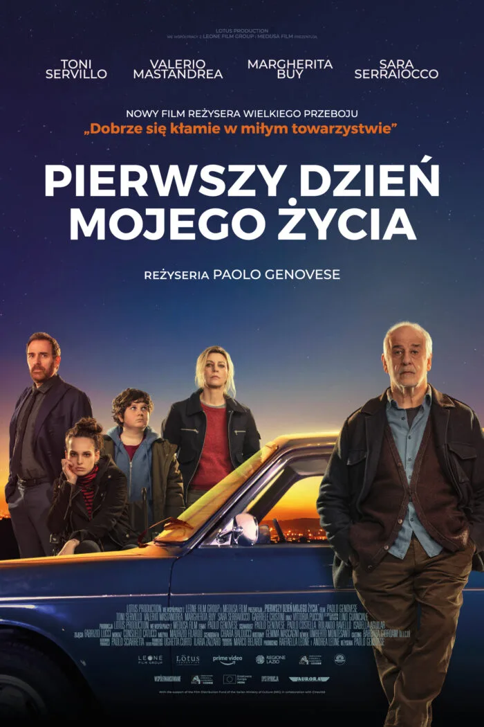 Plakat promujący film "Pierwszy dzień mojego życia". Starszy mężczyzna ubrany swobodnie w ciemną kurtkę, niebieską koszulę, ciemne spodnie stoi na tle granatowego auta. Za samochodem cztery osoby w różnym wieku.